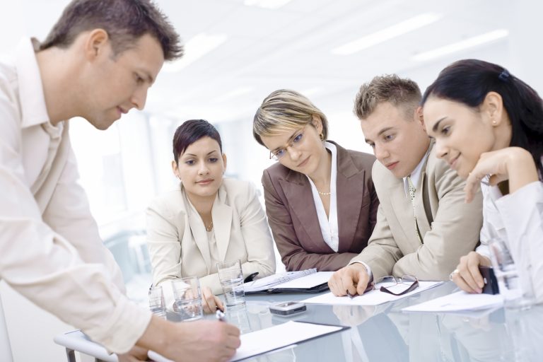 A group of professionals engaged in a meeting around a conference table.