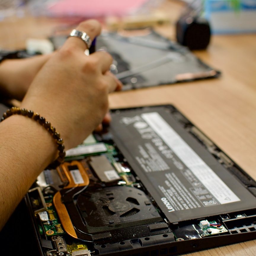 Lets Fix tech together A person repairing a laptop, focusing on the internal components.