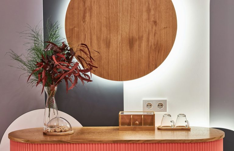 Vase of red foliage on a wooden console with a circular backdrop and soft lighting.