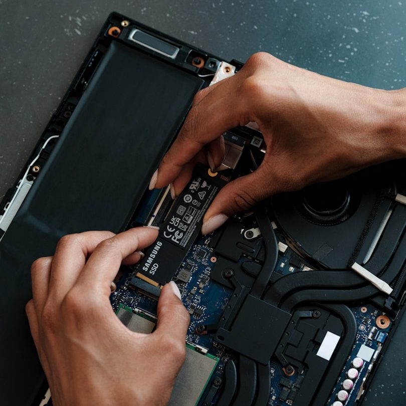 Hands installing a component inside a laptop's open casing.