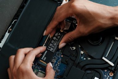 ssd upgrade A person installing a hardware component into a computer's motherboard.