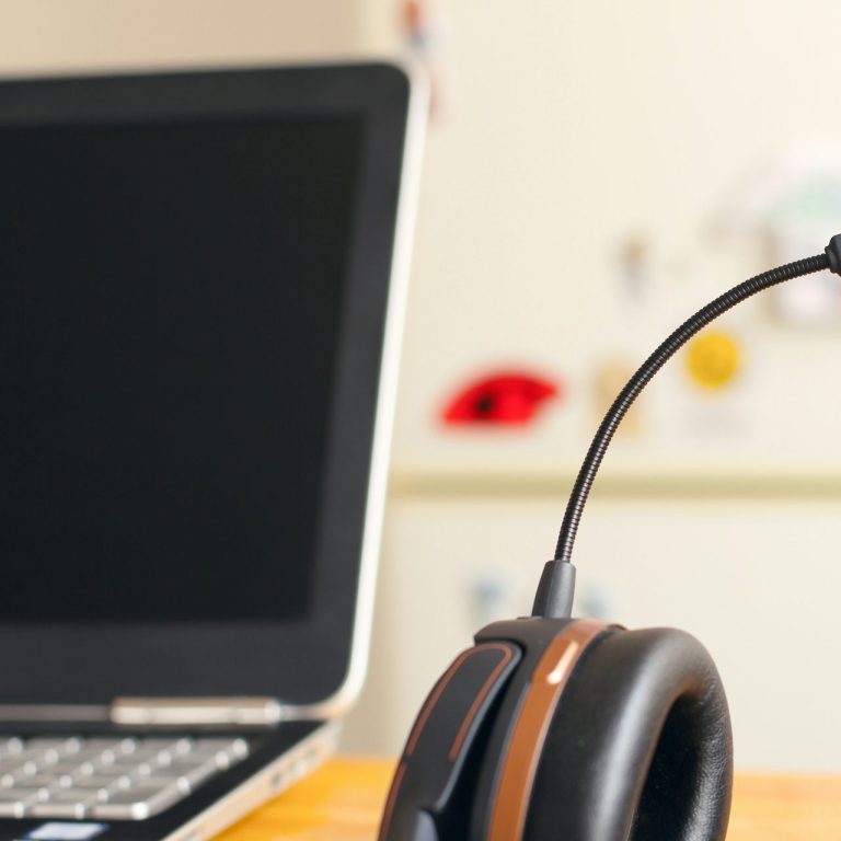 remote it support Black headset with a microphone beside a laptop on a wooden table.