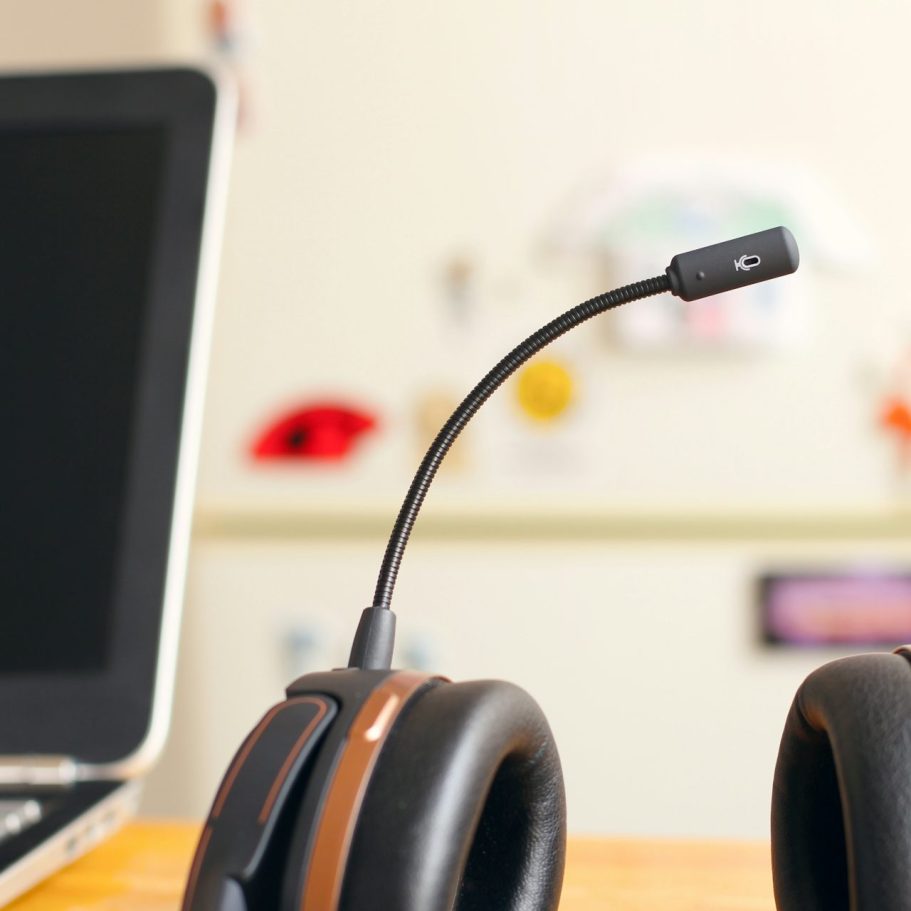 A headset with a flexible microphone placed near a laptop on a desk.