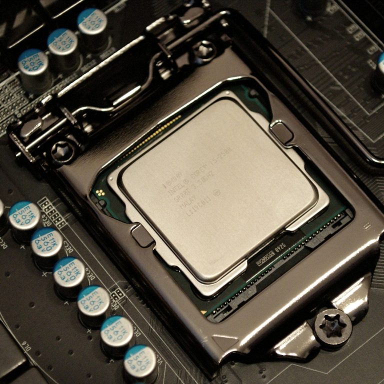 pc and laptop repairs Close-up of a computer CPU mounted on a motherboard with surrounding capacitors.