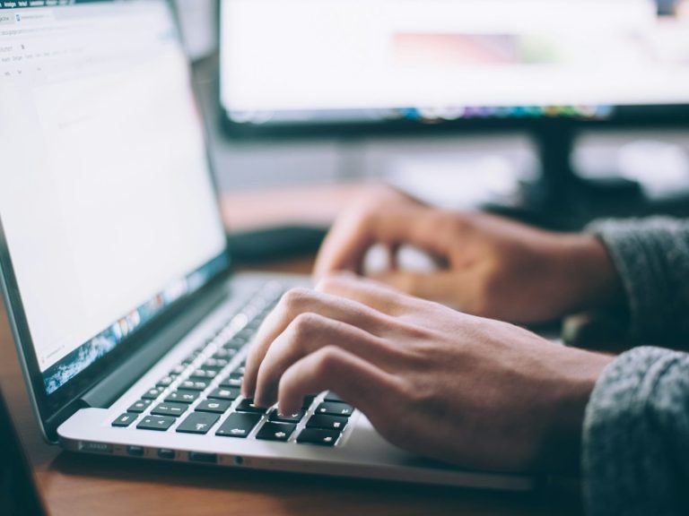 cyber security basics Person typing on a laptop with a blurred screen in the background.